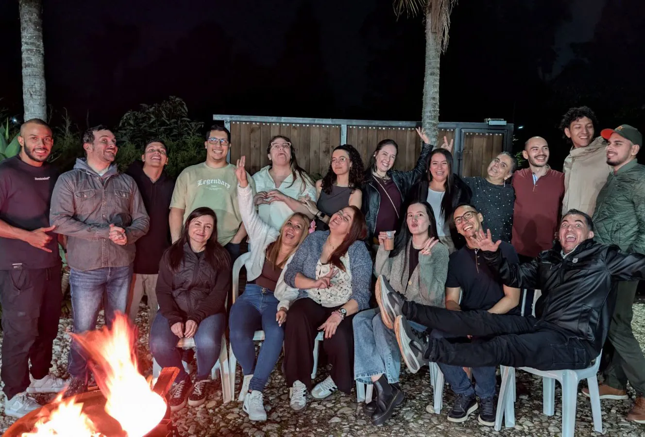 El equipo de Pacífica reunido de noche alrededor de una fogata, posando y riéndose